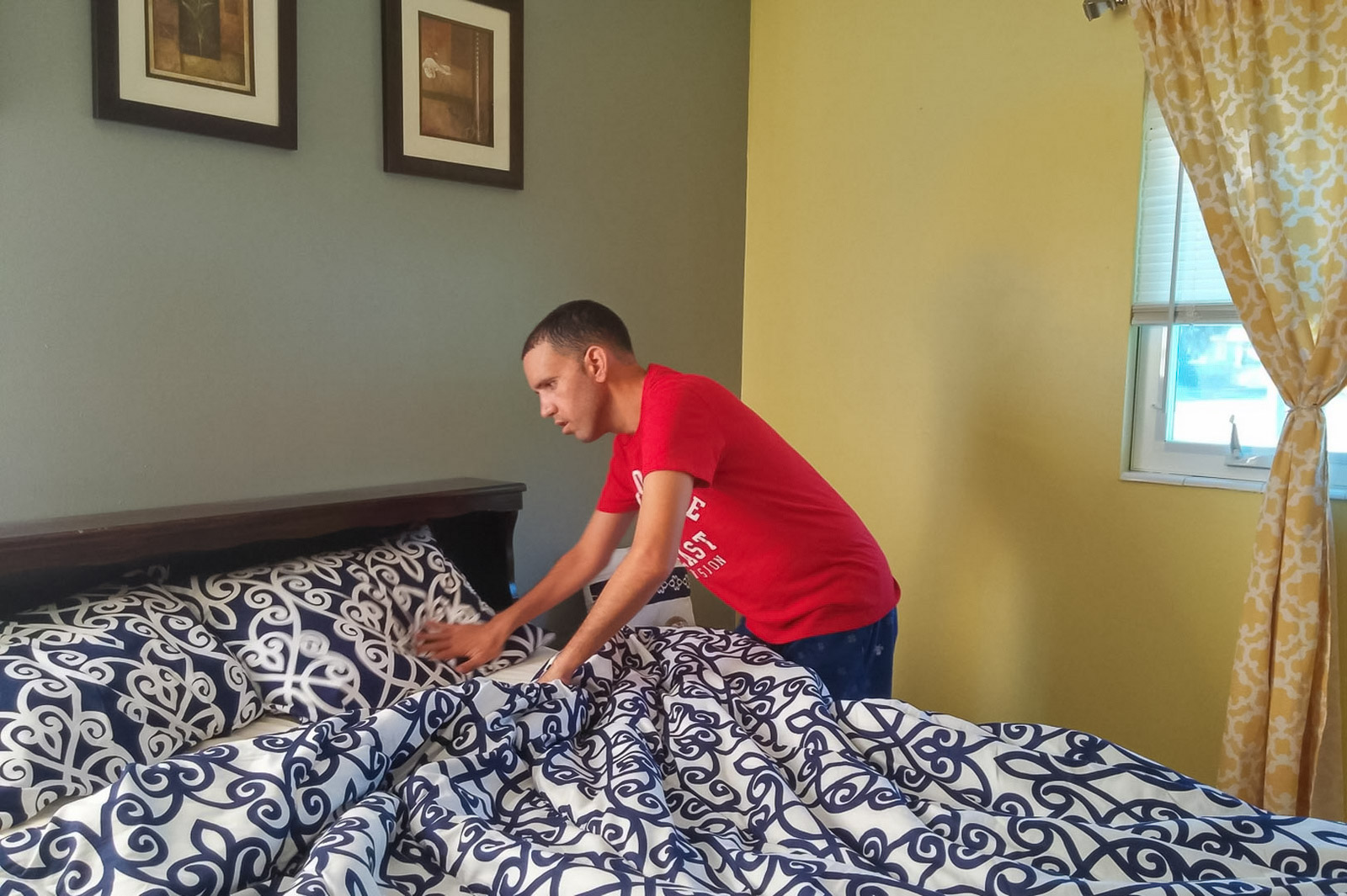 Group home resident learning how to make his bed.