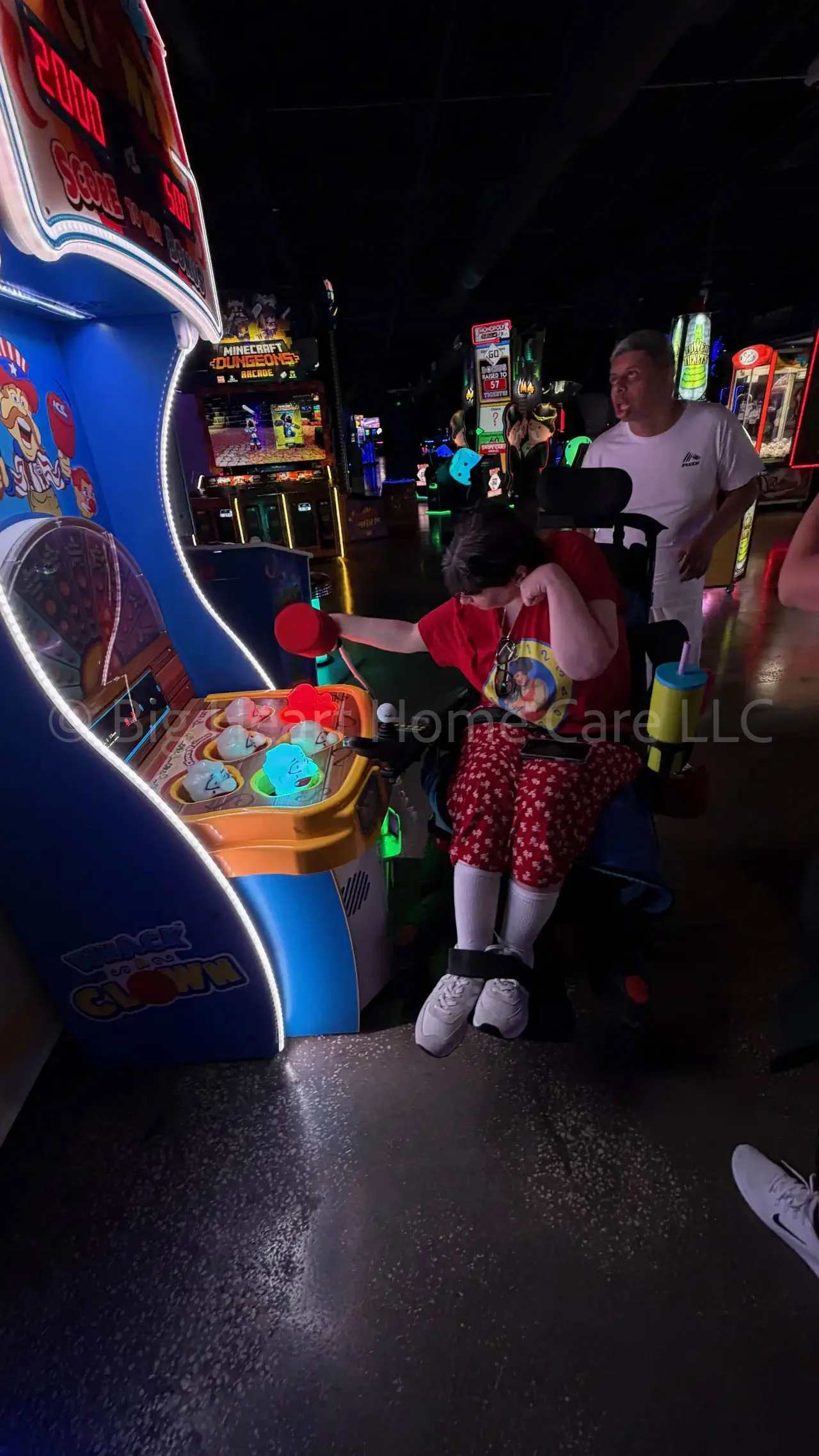 Big Heart Group Home resident playing a fast-paced light-up arcade game at ELEV8 Fun Tampa while staff provides support in a vibrant neon environment.