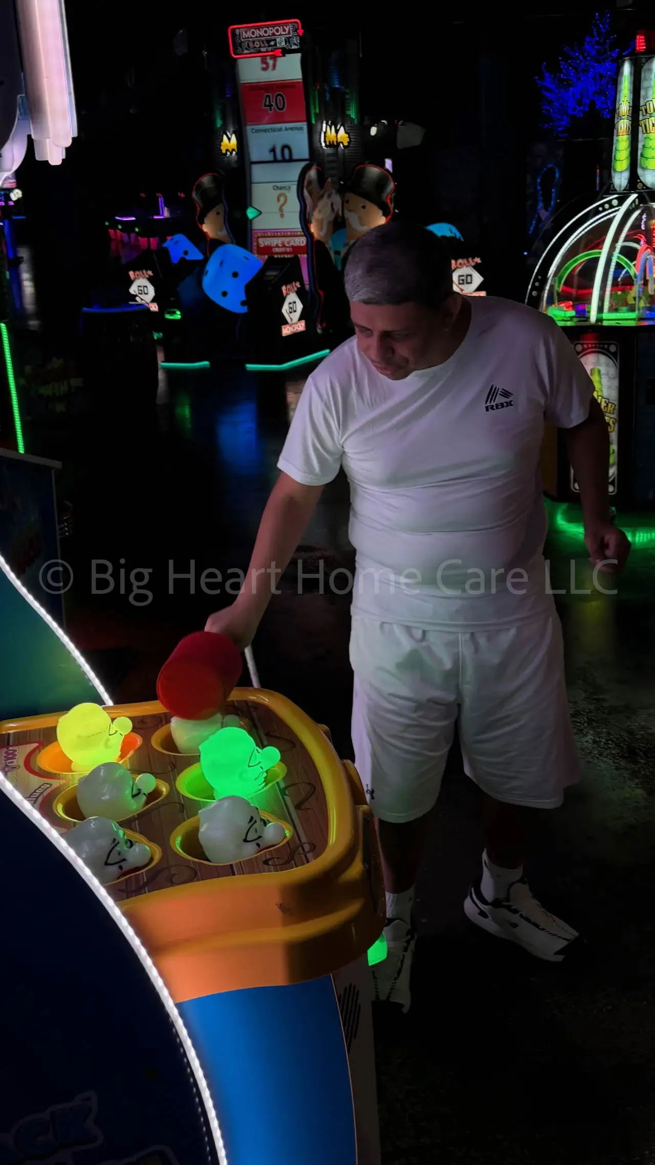 Big Heart Group Home resident playing a glowing reaction-time arcade game with a red mallet at ELEV8 Fun Tampa in Tampa, Florida.