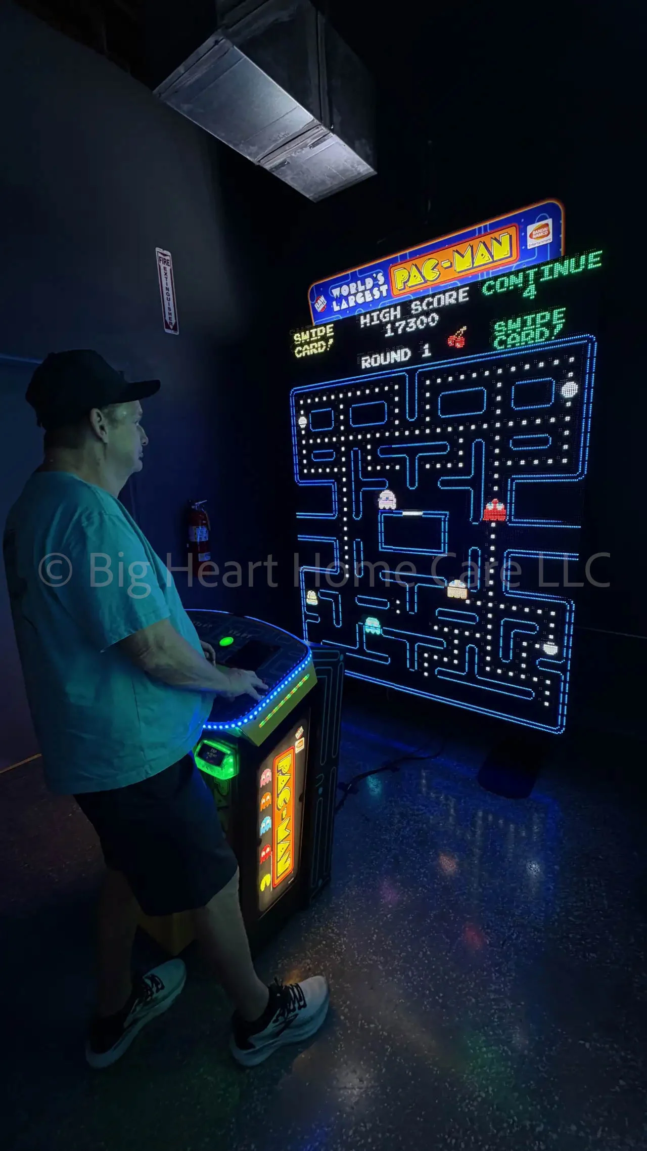 Big Heart Group Home resident playing a large interactive Pac-Man arcade game at ELEV8 Fun Tampa in a neon-lit arcade environment.