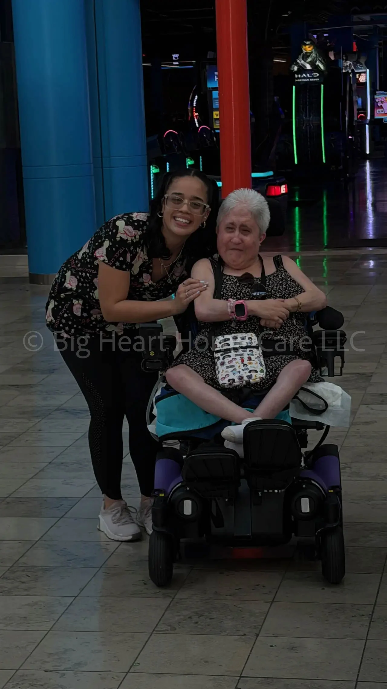 Big Heart Group Home staff member smiling beside a resident in a power wheelchair during a community outing in Tampa, Florida.